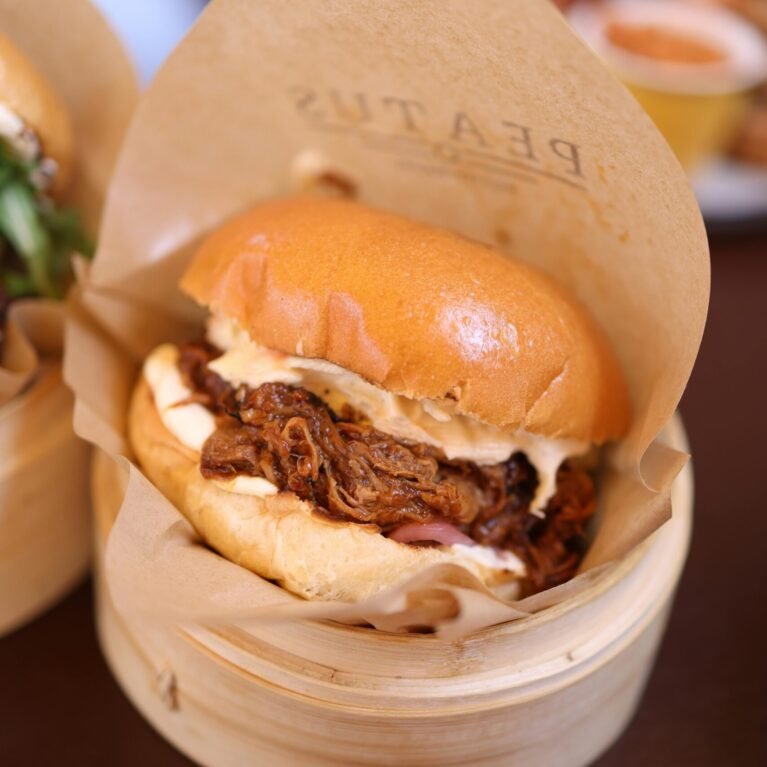 Mouthwatering pulled pork burger served in a wooden container with a rustic ambiance.