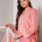 Young woman in pink traditional dress posing gracefully indoors on a staircase.