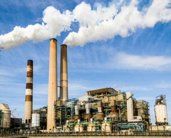 pexels-photo-247763-247763 A large industrial power plant with smokestacks emitting smoke under a blue sky, symbolizing pollution.