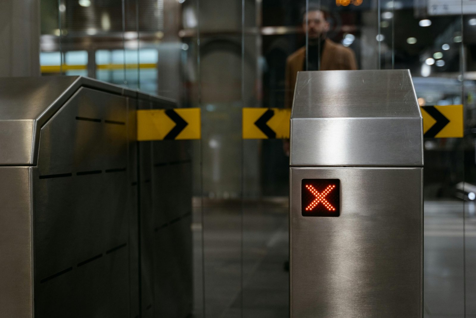 Close-up of a stainless steel ticket barrier with red X signal indicating no entry.