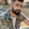 Close-up portrait of a stylish, bearded man outdoors in natural sunlight.
